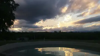 a cloudy sky with a pool of water in a yard at Corral de Pirca in Los Reartes