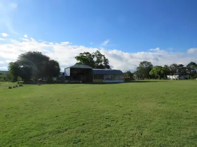 a large green field with a building in the background at Corral de Pirca in Los Reartes