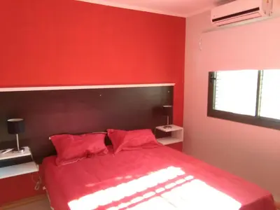 a red bedroom with a bed with red sheets and pillows at Magenta Departamentos in Mina Clavero