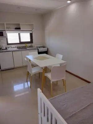 a kitchen with a table and chairs in a room at Magenta Departamentos in Mina Clavero