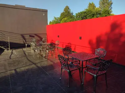a patio with tables and chairs and a red wall at Magenta Departamentos in Mina Clavero