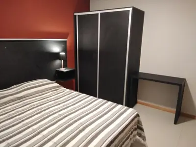 a bedroom with a bed and a black cabinet at Magenta Departamentos in Mina Clavero