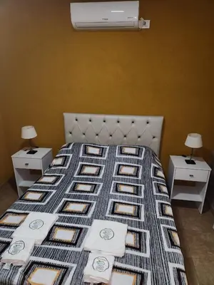 a bed with a blanket and two nightstands with two lamps at Complejo M&M in Bialet Massé