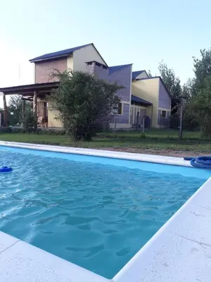 a swimming pool in front of a house at Cabañas Vientos del Sur in Villa Yacanto