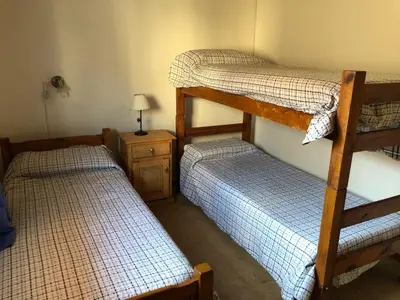 a room with two bunk beds and a table with a lamp at Dpto El Nilo Carlos Villa Paz in Villa Independencia