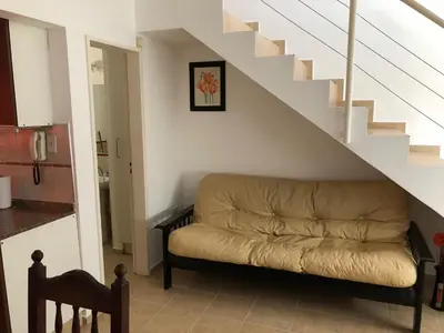 a living room with a couch under the stairs at Dpto El Nilo Carlos Villa Paz in Villa Independencia