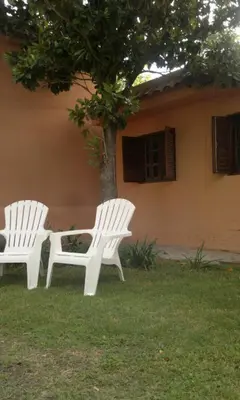 two white chairs sitting in front of a house at Abbá Departamentos in Mina Clavero