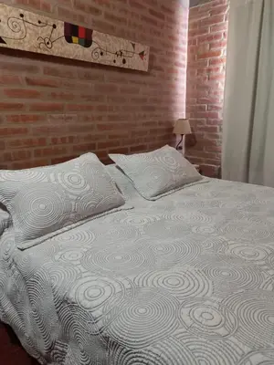 a bedroom with a white bed with a brick wall at Departamento Estela Marys in Mina Clavero
