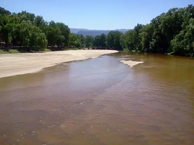 a body of water with a beach and trees at Departamento Estela Marys in Mina Clavero