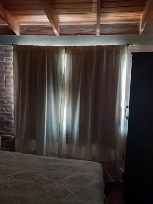 a bedroom with a bed and a curtain at Departamento Estela Marys in Mina Clavero