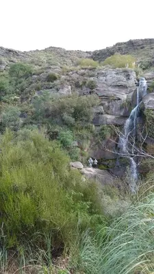 a waterfall on the side of a hill with grass at Cabañas Buen Ayre in Villa Rumipal