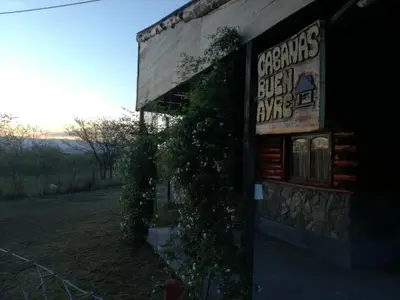 a building with a sign on the side of it at Cabañas Buen Ayre in Villa Rumipal
