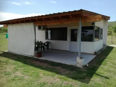 a small white house with a large patio at Cabañas Buen Ayre in Villa Rumipal