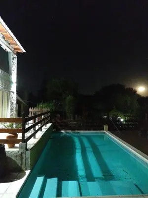 a swimming pool at night with the lights on at Talita Cumi in Villa Santa Cruz del Lago