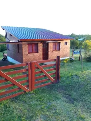 a house with a wooden fence in front of it at cabaña La Retama in Villa Yacanto