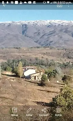 a building in a field with mountains in the background at cabaña La Retama in Villa Yacanto