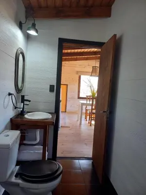 a bathroom with a toilet and a sink and a door at Cabaña de Campo - Valle de Calamuchita - Sierras de Córdoba in San Clemente
