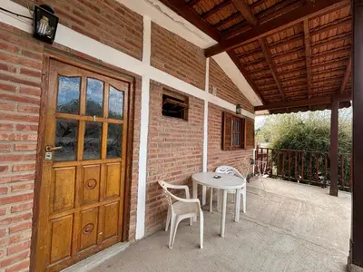 a patio with a table and chairs and a wooden door at Departamentos Los Álamos in Mina Clavero