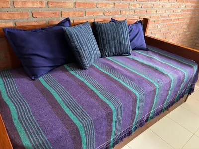 a bed with two pillows and a brick wall at Departamentos Los Álamos in Mina Clavero