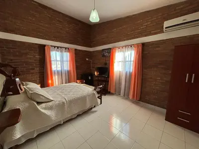 a bedroom with a bed and two windows at Departamentos Los Álamos in Mina Clavero