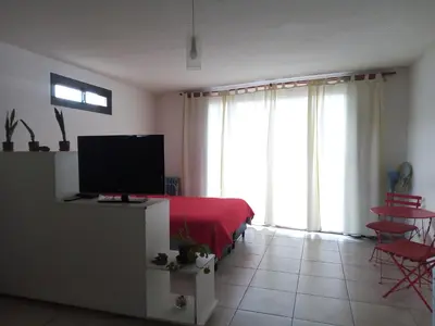 a bedroom with a bed with a red blanket and large windows at Departamento LA PAZ in Villa Carlos Paz