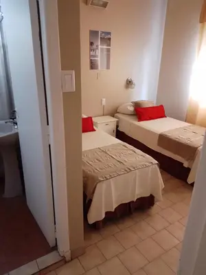two beds in a small room with a bathroom at Camino Real Hotel in Cordoba
