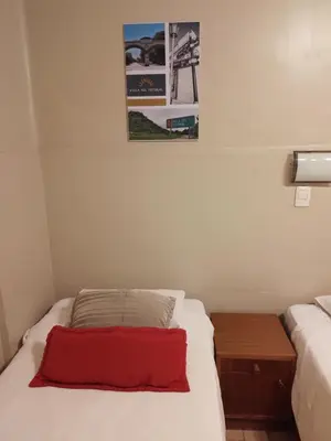 a small room with a bed with a red pillow at Camino Real Hotel in Cordoba