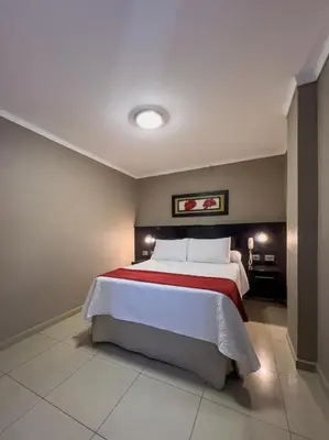 a bedroom with a bed with a red and white blanket at Hotel Everest in Cordoba