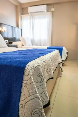 a bedroom with two beds and a blue blanket at Hotel Everest in Cordoba