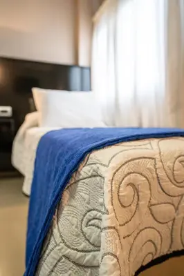 a bedroom with a bed with a blue blanket at Hotel Everest in Cordoba