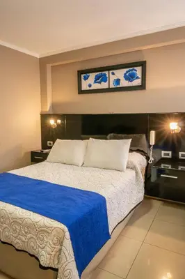 a bedroom with a large bed with a blue blanket at Hotel Everest in Cordoba