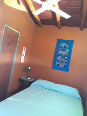 a bedroom with a bed with a blue blanket and a ceiling at Sierra Magenta in Los Hornillos