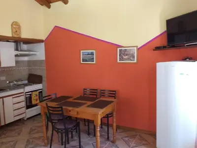 a kitchen with a table with chairs and a red wall at Sierra Magenta in Los Hornillos