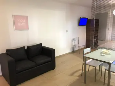 a living room with a black couch and a table at BOULEVARD departamentos in Mina Clavero