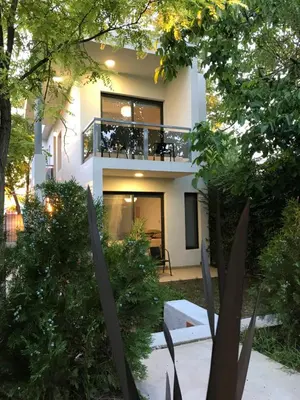 a white house with a balcony in the yard at BOULEVARD departamentos in Mina Clavero