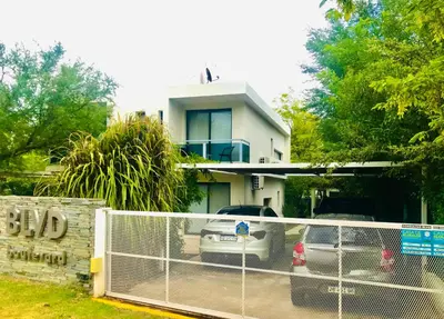 a white house with a car parked in front of it at BOULEVARD departamentos in Mina Clavero