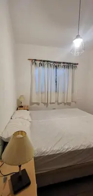 a bedroom with a bed with white sheets and a window at Villa Elena Icho Cruz in Villa Icho Cruz