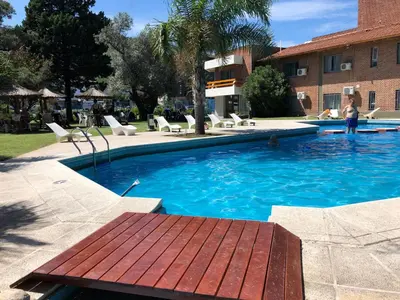 a swimming pool with a wooden bench in front of a building at Riviera Hotel & Spa in Villa Carlos Paz
