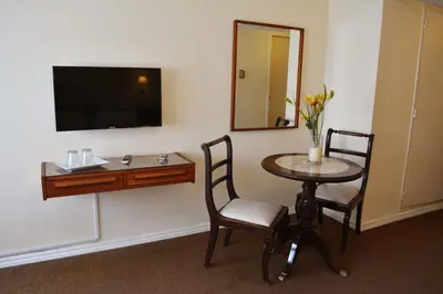 a room with a table and a mirror and a television at Hotel Sussex in Cordoba