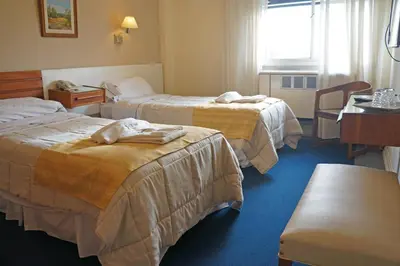 a hotel room with two beds and a table at Hotel Sussex in Cordoba