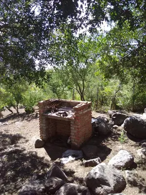 a brick fireplace in a field with trees and rocks at Antiguo Molle in Merlo