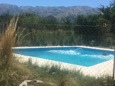 a swimming pool with a fence and mountains in the background at Antiguo Molle in Merlo