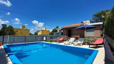 a swimming pool with two chairs and an umbrella at Blacky House in Villa Carlos Paz