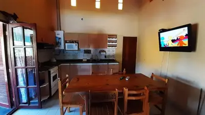 a kitchen with a wooden table and a television on the wall at Blacky House in Villa Carlos Paz