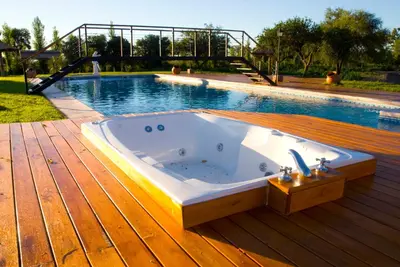 a hot tub sitting on a deck next to a swimming pool at Lauquen Pilmaiquen y spa in Merlo