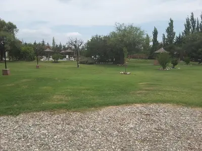 a large green field with trees and huts at Lauquen Pilmaiquen y spa in Merlo