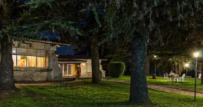 a house in a park at night with trees at Hotel Parque Siquiman in Villa Carlos Paz
