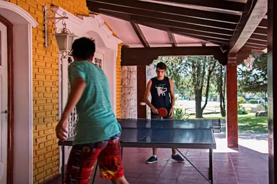 two young men playing a game of ping pong at Hotel Parque Siquiman in Villa Carlos Paz