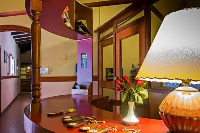 a table with a lamp and a vase of flowers on it at Hotel Parque Siquiman in Villa Carlos Paz