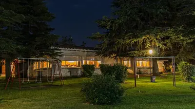 a house with a playground in the yard at night at Hotel Parque Siquiman in Villa Carlos Paz